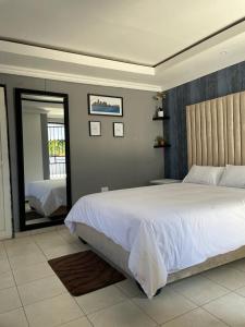 1 dormitorio con 1 cama blanca grande y espejo en Yello guest house, en Vanderbijlpark