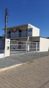 a white fence in front of a building at Pousada Parque Central in Penha