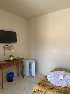 a room with a bed and a desk and a television at Pousada Parque Central in Penha