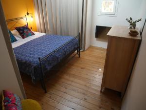 1 dormitorio con 1 cama y suelo de madera en Chambre et salon climatisés chez l'habitant dans une maison de village de charme, en Passa
