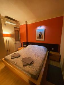 a bedroom with a bed with an orange wall at Sunshine Place in Elbasan