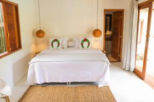 Schlafzimmer mit einem Bett mit weißer Bettwäsche und einem Teppich in der Unterkunft Suites Taipe in Trancoso