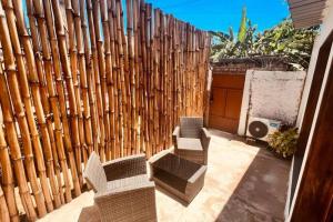 a patio with two chairs and a wooden fence at Refúgio Compacto in São Tomé