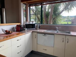 a kitchen with white cabinets and a sink and a window at Ridley Manor in Ohakune