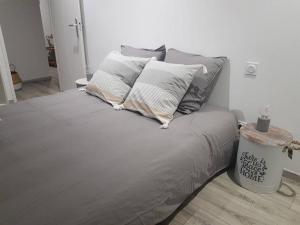 een bed met grijze lakens en kussens in een kamer bij Très beau gîte neuf et fonctionnel aux portes du Mans et du circuit in Teloché