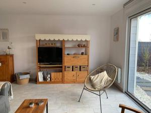 een woonkamer met een tv en een stoel bij Très beau gîte neuf et fonctionnel aux portes du Mans et du circuit in Teloché