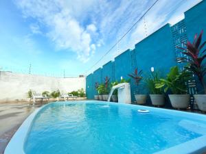 a large swimming pool with a blue wall and chairs at Wind Village Chalés in São Miguel do Gostoso
