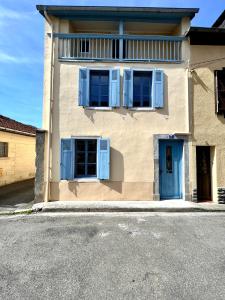 a house with blue shutters on the side of it at Le gîte du bonheur in Bagnères-de-Bigorre