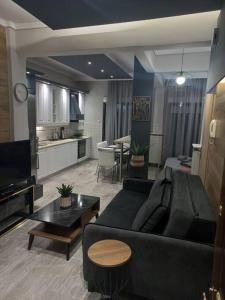 a living room with a black couch and a kitchen at Central 4 Modern Apartment with free parking in Serres