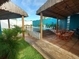 a patio with a table and chairs and a pool at Wind Village Chalés in São Miguel do Gostoso