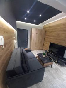 uma sala de estar com um sofá preto e uma televisão em Central 4 Modern Apartment with parking em Serres