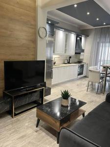 a living room with a large television and a kitchen at Central 4 Modern Apartment with free parking in Serres