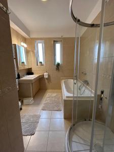 y baño con ducha, bañera y lavamanos. en Villa Hegyalja en Balatonkenese