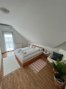 a white bedroom with a large bed and a plant at Villa Hegyalja in Balatonkenese