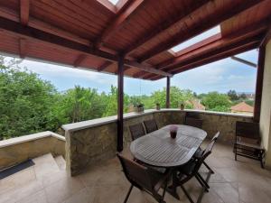 patio con mesa de madera y sillas en el balcón en Villa Hegyalja en Balatonkenese