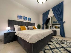シャルジャにあるWaterfront Royal 3BR apartmentのベッドルーム1室(青いカーテン付きの大型ベッド1台付)