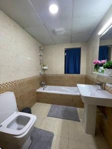 a bathroom with a toilet and a sink and a tub at Waterfront Royal 3BR apartment in Sharjah