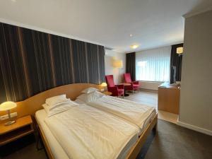 een hotelkamer met een groot bed en 2 stoelen bij Landhotel Alberts in Heijenrath