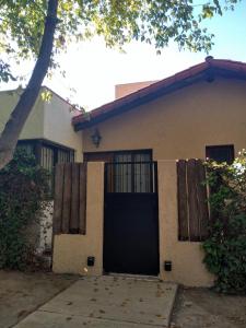 a house with a black door and a fence at Acogedor departamento Los Ranchos in Chacras de Coria