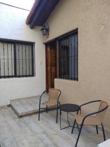 a patio with two chairs and a table and a building at Acogedor departamento Los Ranchos in Chacras de Coria