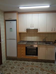 eine Küche mit weißen Schränken und einem Kühlschrank in der Unterkunft Apto Cortegada in Vilagarcia de Arousa