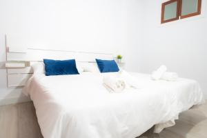 a bedroom with a white bed with blue pillows at Alojamientos el Bajón in La Restinga