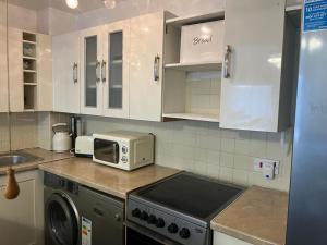 uma cozinha com fogão forno ao lado de um micro-ondas em LONDON 1 BED COSY HOUSE em Norwood