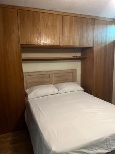 Schlafzimmer mit einem weißen Bett und Holzschränken in der Unterkunft LONDON 1 BED COSY HOUSE in Norwood