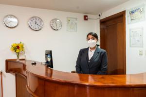 Eine Frau mit Maske in einem Büro. in der Unterkunft Kenamari Hotel Cusco in Cusco