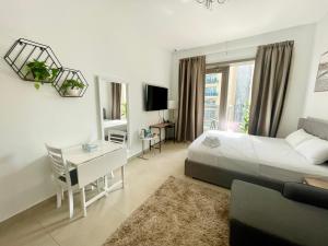 ein Hotelzimmer mit einem Bett, einem Schreibtisch und einem TV in der Unterkunft Super Elegant studio apartment-Sparkle tower By SWEET HOMES in Dubai