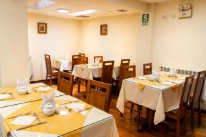 a dining room with tables and chairs with white tablecloths at Kenamari Hotel Cusco in Cusco