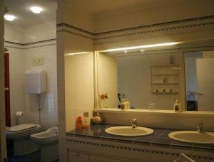 a bathroom with two sinks and a mirror and a toilet at Villa Elena in Manerba del Garda
