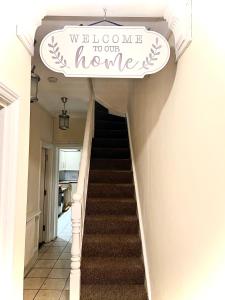 een trap met een welkom op ons bord bij Aldgate Holiday Rooms in Londen