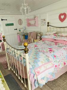 a bedroom with a bed with a pink and blue quilt at Shabby Shack near Charlestown & The Eden Project in St Austell