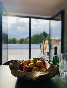 un tazón de manzanas en una mesa con una botella de vino en Ferienwohnung Nalbach Wohnung 1, en Nalbach