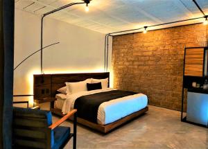 - une chambre avec un lit et un mur en briques dans l'établissement Hotel Tila, à Cholula