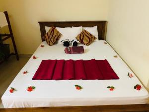 a bed with red sheets and a red bag on it at Yal's Town Inn in Jaffna