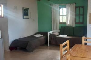 a room with two beds and a table and a window at Casas HG-Desayuno sencillo entregado al check in-Pileta climatizada en predio a 2 kilómetros-Acepta mascotas bajo petición-Cochera para 1 auto in Huerta Grande