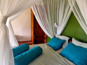 1 cama con almohadas y cortinas azules en una habitación en Ilasan cottage., en Tomohon
