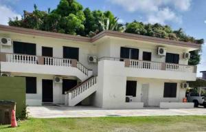 a white house with a hill in the background at Beautiful Condos walking distance to a private beach! in Tamuning