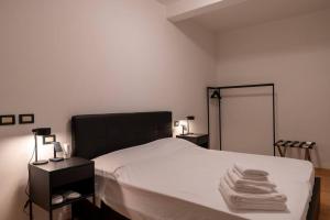 a bedroom with a bed with white sheets and towels at Piazza Duomo Cathedral View in Brescia