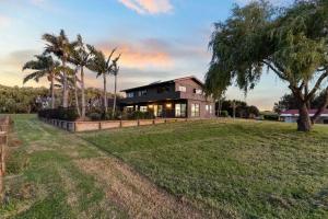 une maison sur une colline herbeuse avec un arbre dans l'établissement franklin chapel, à Clarks Beach