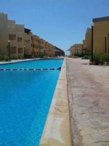 ein Pool mit blauem Wasser neben den Gebäuden in der Unterkunft Blue Lagoon Village Ras Sidr (قرية بلولاجون راس سدر) (عائلات فقط) in Ras Sudr