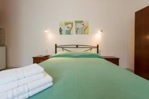 - une chambre avec un lit vert et des serviettes dans l'établissement Senka studios, à Parga