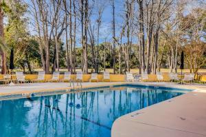 a swimming pool with lounge chairs and trees at Beckenham 209 in Hilton Head Island