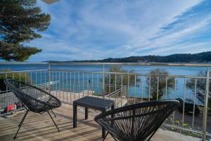 two chairs and a table on a deck with a view of the water at Tisno Laurel Apartments in Tisno