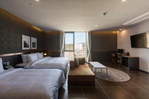 ein Hotelzimmer mit 2 Betten und einem Schreibtisch in der Unterkunft Browndot hotel Guseo in Busan