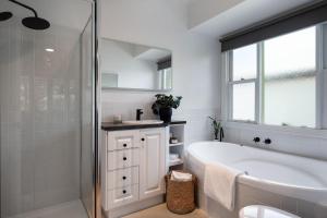 a white bathroom with a tub and a sink at Sunshine House in Daylesford