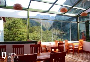 une salle à manger avec des tables et des chaises ainsi qu'une grande fenêtre dans l'établissement Hotel Qoya Palace - Machupicchu, à Machu Picchu