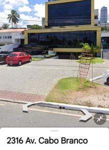 un coche rojo estacionado en un estacionamiento frente a un edificio en MAR DO CABO BRANCO YELLOW residence en João Pessoa